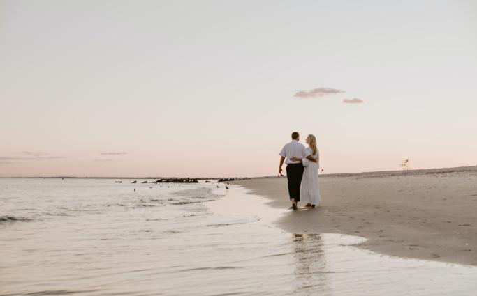 Couple walking on beach at sunset